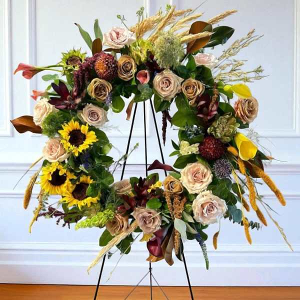 Large floral wreath on a black stand with roses and sunflowers