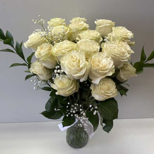 Bouquet of cream roses in a glass vase with baby's breath
