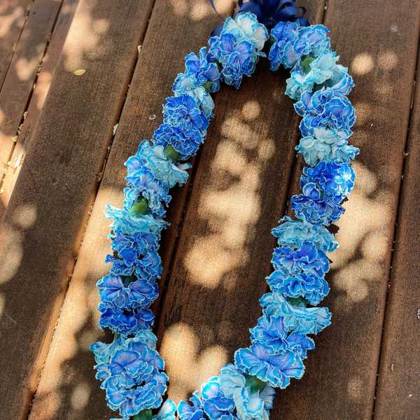 Blue and light blue flower lei on a wooden surface