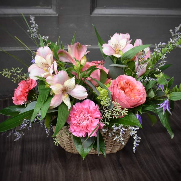 Pink and white flowers arranged in a woven basket