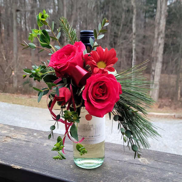 Pink roses and a red daisy in a wine bottle vase