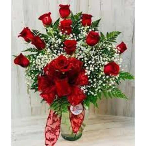 Red roses arranged in a glass vase with baby's breath and greenery