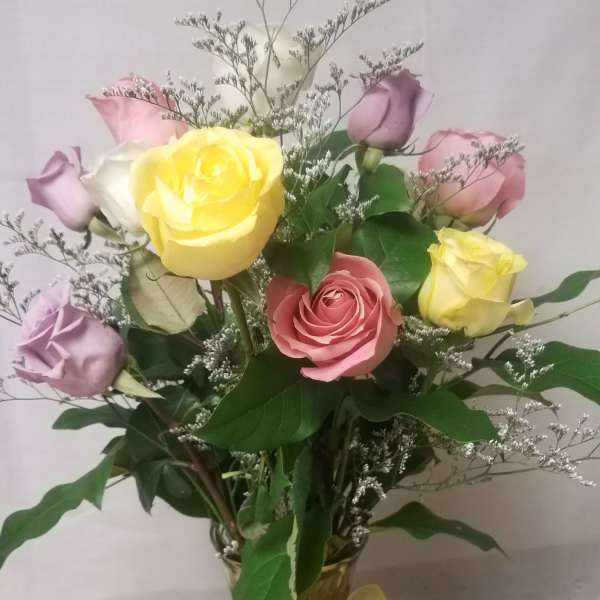 Bouquet of pastel roses in a glass vase with a yellow ribbon