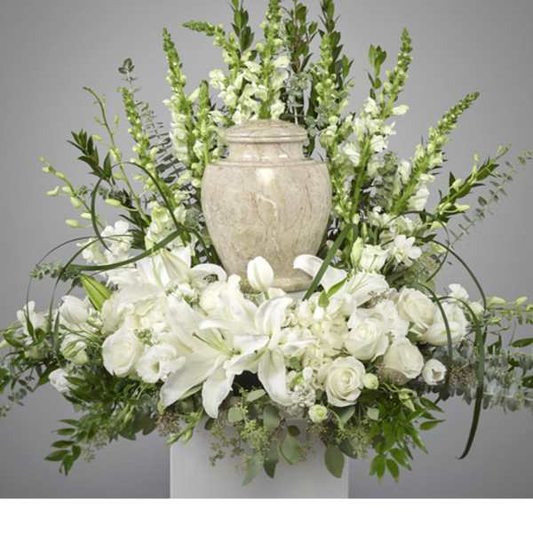 White floral arrangement with lilies and roses around a stone urn