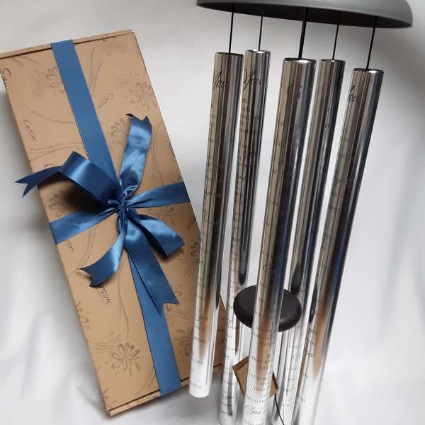 Gift box with blue ribbon beside a set of silver wind chimes