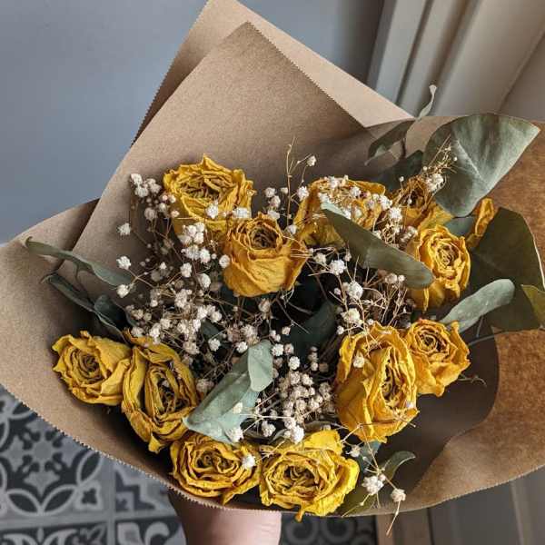 Bouquet of dried yellow roses with baby's breath and eucalyptus in brown paper