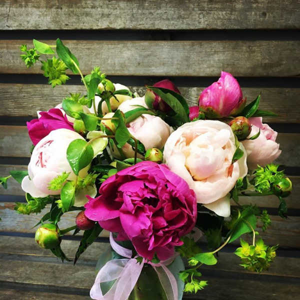 Bouquet of pink and white peonies in a glass vase with a ribbon