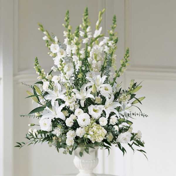 White floral arrangement in a white pedestal vase