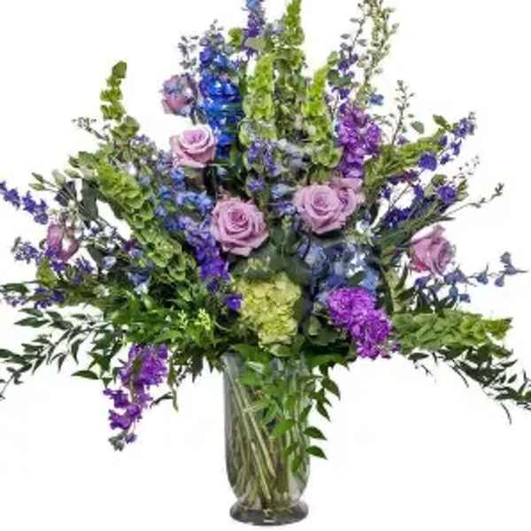 Tall bouquet of purple and blue flowers in a glass vase