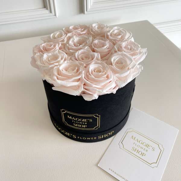 Pale pink roses arranged in a black round box