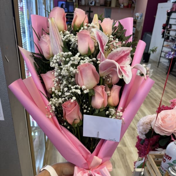 Pink roses and lilies in pink wrap with a satin bow