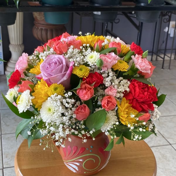 Mixed bouquet of roses, carnations, and chrysanthemums in a painted ceramic vase