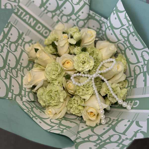 Cream roses and pale green carnations in teal wrapping with pearl strands