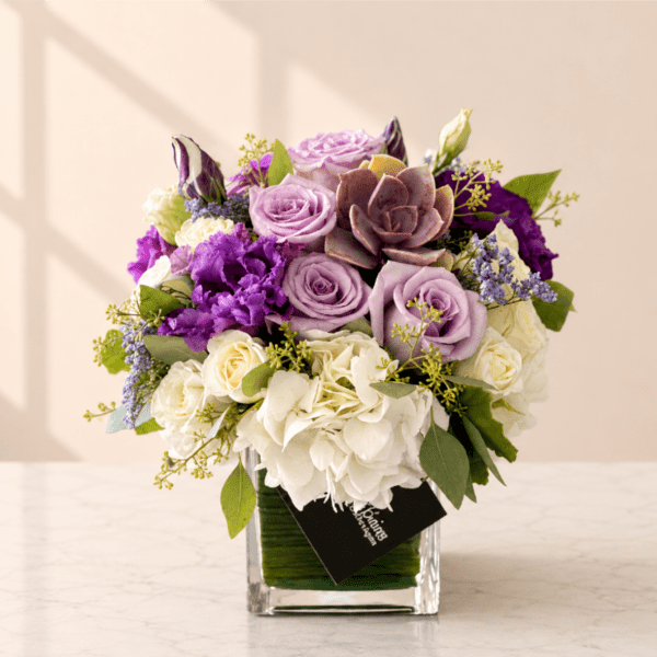 Lavender and white rose bouquet in a clear square vase