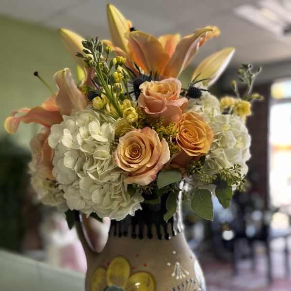 Peach roses and white hydrangeas in a painted ceramic vase