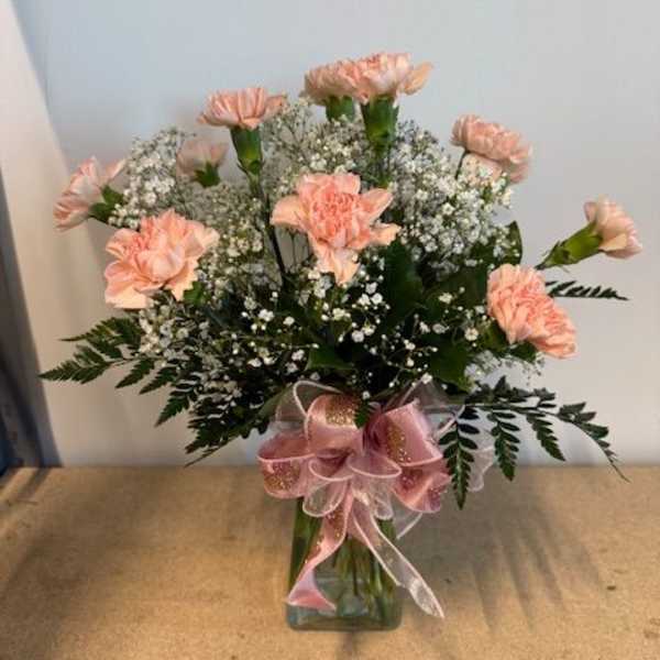 Pink carnations in a glass vase with baby's breath and a pink ribbon