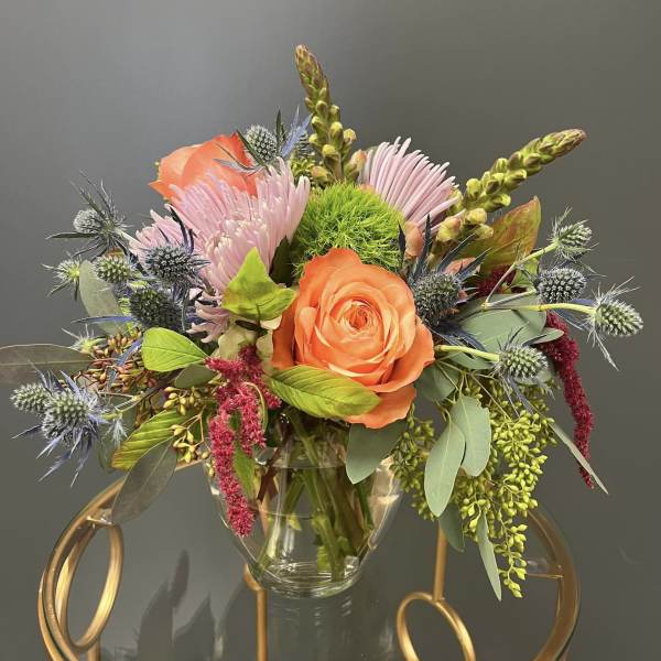 Orange rose and pink blooms in a clear glass vase