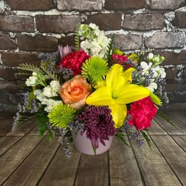 Mixed bouquet in a pink vase with a yellow lily and colorful blooms