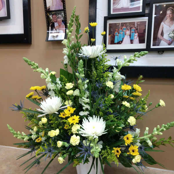 Tall mixed floral arrangement in a white vase with white and yellow blooms