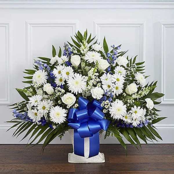 White daisies and roses arranged in a blue ribboned vase