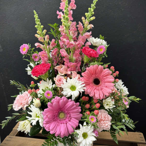 Pink and white mixed flower arrangement in a white basket vase