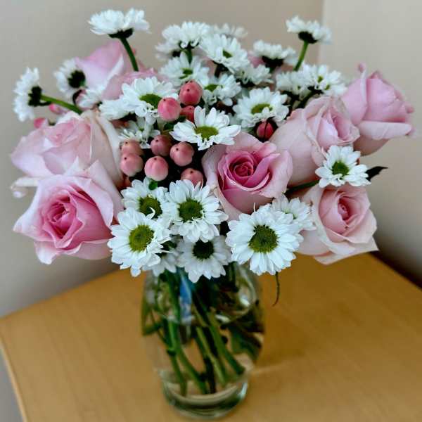 Pink roses and white daisies arranged in a clear glass vase