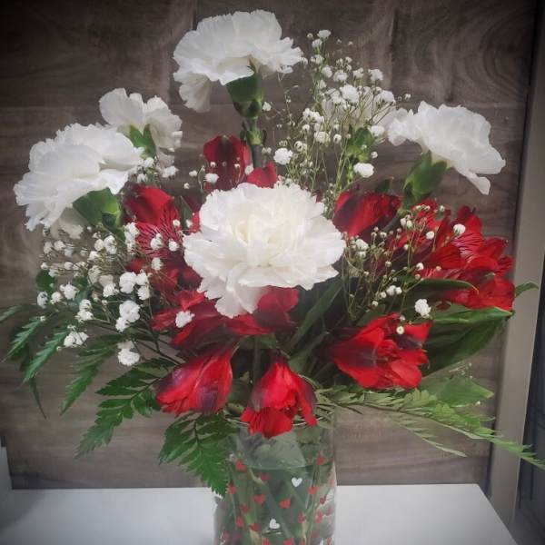 Red and white carnations in a clear heart-patterned vase