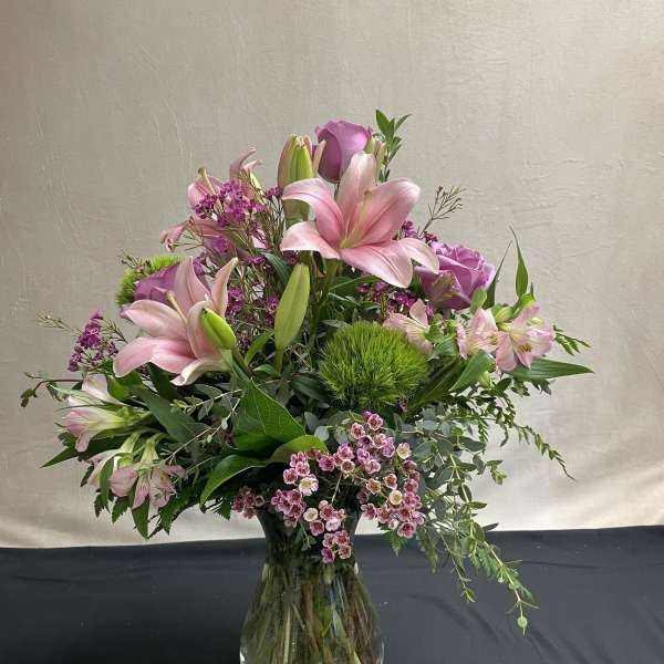 Pink lilies and roses arranged in a clear glass vase
