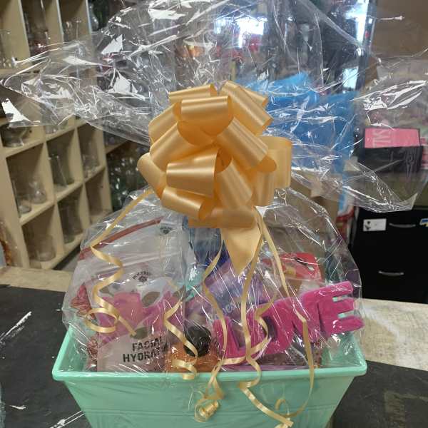 Gift basket with skincare items wrapped in clear cellophane and topped with a gold bow