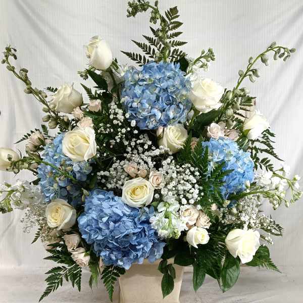 Blue hydrangeas and white roses in a cream vase