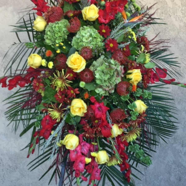 Tall standing floral spray with red and yellow flowers on a black easel