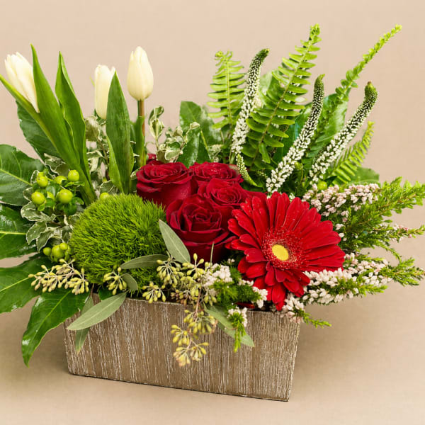 Red roses and a red gerbera daisy in a rectangular vase with white tulips
