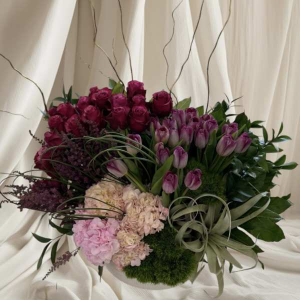 Bouquet of purple roses, tulips, and hydrangeas with decorative grasses