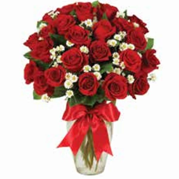 Bouquet of red roses with small white filler flowers in a glass vase