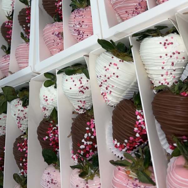 Boxes of chocolate-covered strawberries in pink, white, and dark chocolate