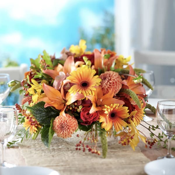 Orange and yellow mixed flower centerpiece in a low vase