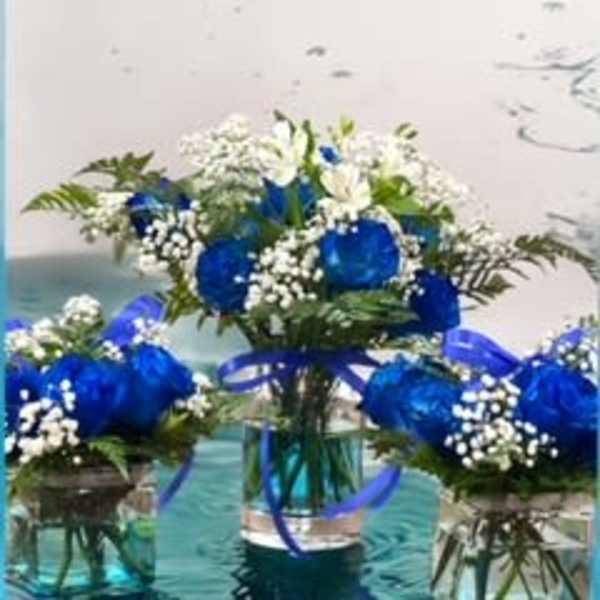 Blue and white flower arrangements in glass vases with ribbon