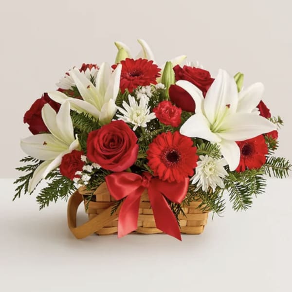 Red and white flower arrangement in a wicker basket with a red ribbon