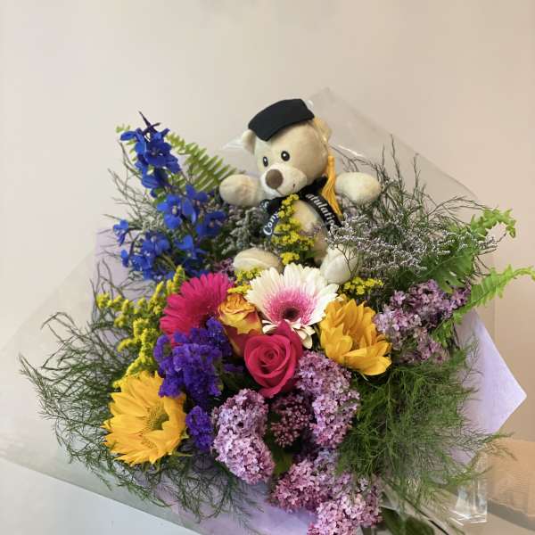 Bouquet of mixed flowers with a teddy bear in a graduation cap