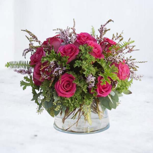 Pink rose bouquet in a clear glass vase with mixed greenery