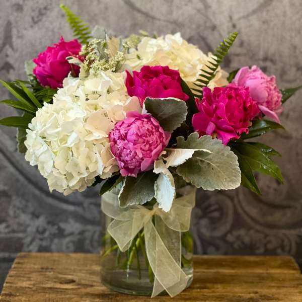 Pink and white floral bouquet in a glass vase with a sheer ribbon