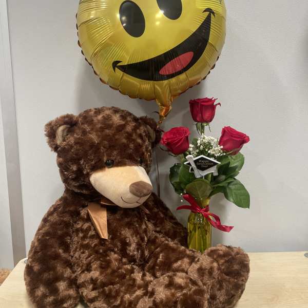 Teddy bear with a smiley-face balloon and a small rose bouquet