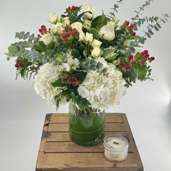 White floral arrangement in a glass vase with red berry accents