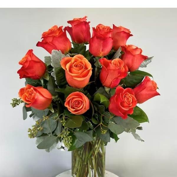 Arrangement of orange roses in a clear glass vase on a round white table