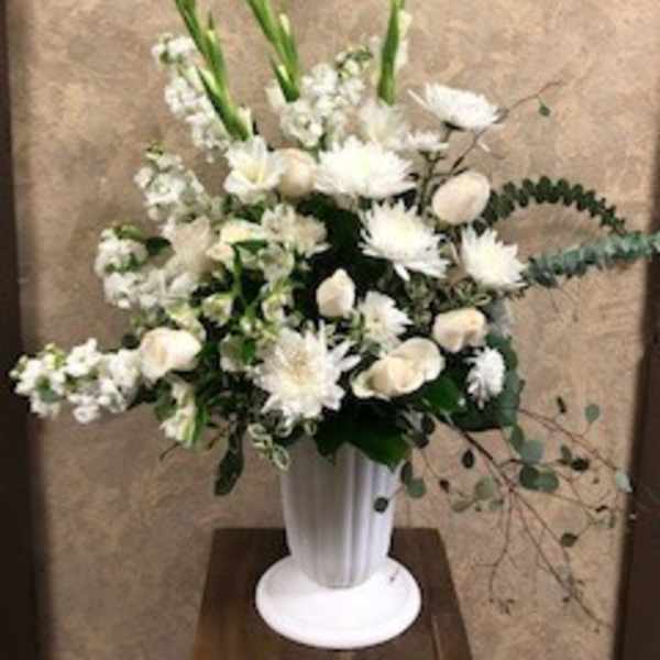 White floral arrangement in a tall white vase with long green stems