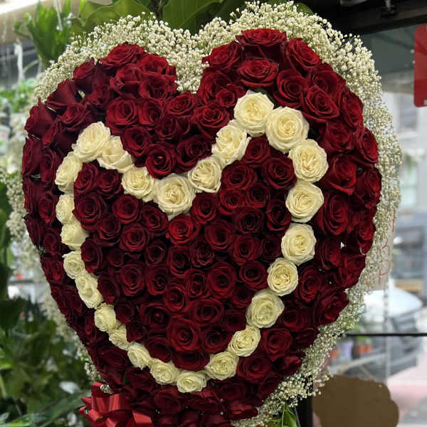 Heart-shaped rose arrangement with red and cream roses and a red ribbon