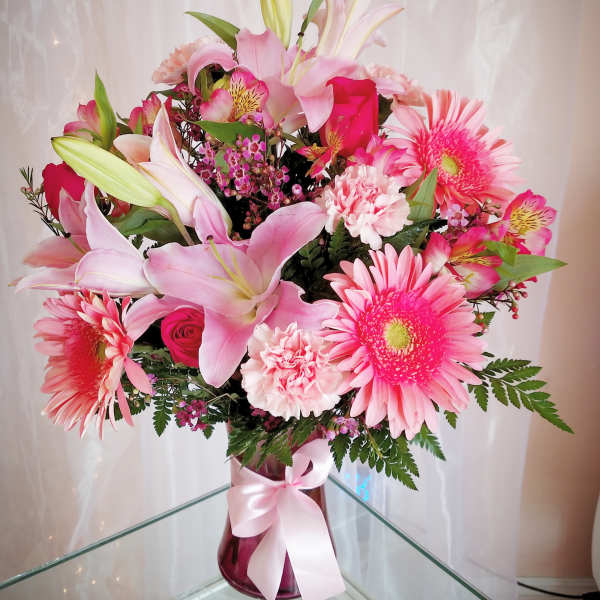 Pink and white mixed bouquet with lilies, gerbera daisies, and carnations in a glass vase