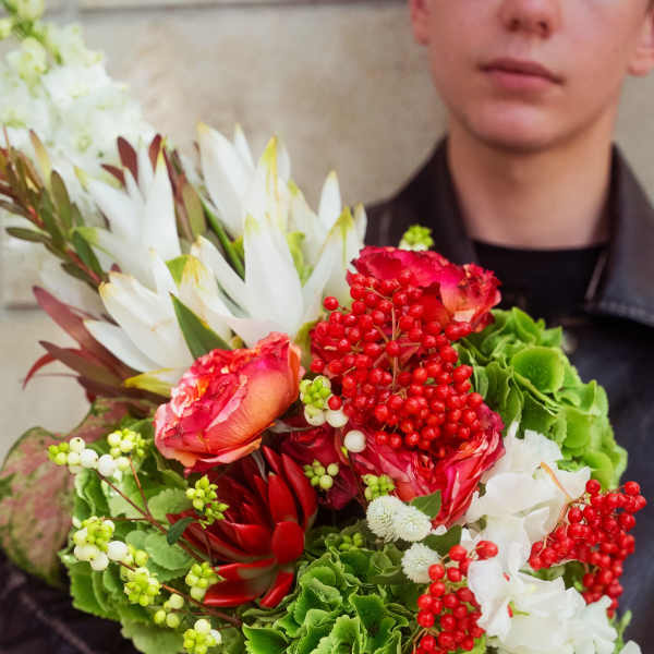 Person holding a colorful bouquet with white and red flowers