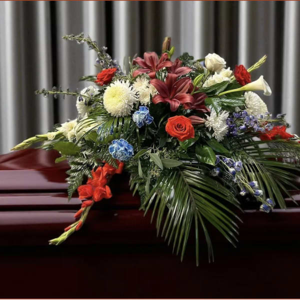 Casket spray with red, white, blue, and cream flowers