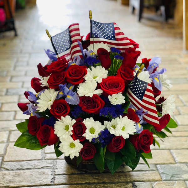 Red roses and white daisies arranged with small American flags